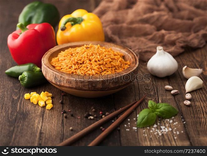 Wooden bowl with long grain basmati vegetable rice on wooden background with sticks and paprika pepper with corn,garlic and basil.