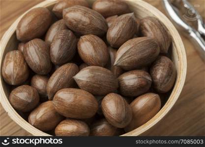 Wooden bowl with whole pecan nuts