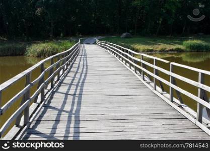 Wooden bridge across the river against the backdrop wood of deciduous trees