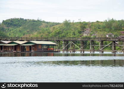 Wooden bridge across the river. The mountain in the back and on both sides of the river.