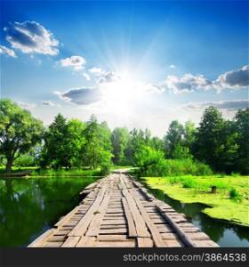 Wooden bridge on a silent river at sunny day