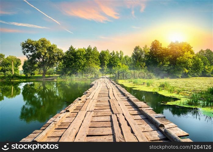 Wooden bridge on a silent river at sunset. Wooden bridge at sunset