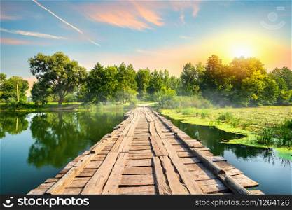 Wooden bridge on a silent river at sunset. Wooden bridge at sunset