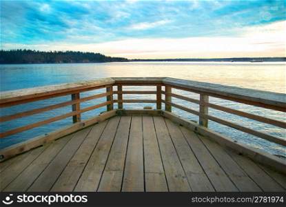 Wooden bridge on the sea coast with sunset and clouds