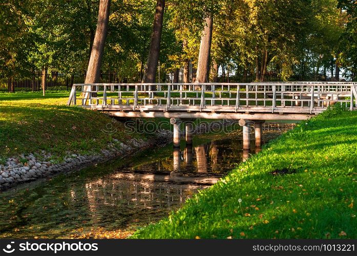 Wooden bridge over the river in the autumn park. Bridge over the river in the park. Autumn day