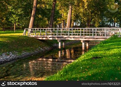 Wooden bridge over the river in the autumn park. Bridge over the river in the park. Autumn day