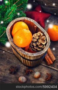 Wooden bucket with tangerines. Wooden bucket with tangerines and pine cones on the background of Christmas trees and spices