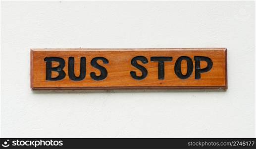 wooden bus stop sign on a white wall