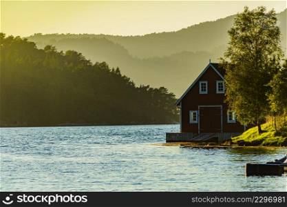 Wooden cabin house on water fjord shore. Summer landscape in Norway, Scandinavia. Wooden cabin on fjord shore, Norway