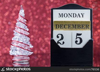 Wooden calendar and Christmas tree reflection on glass table over red background
