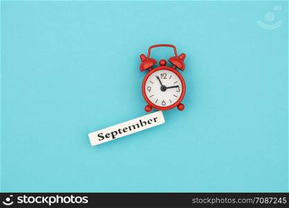 Wooden calendar autumn month September and red alarm clock on blue paper background. Concept Hello September. Creative Top view Flat Lay Minimal style.. Wooden calendar autumn month September and red alarm clock on blue paper background. Concept Hello September. Creative Top view Flat Lay Minimal style