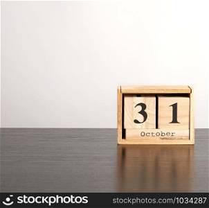 wooden calendar of cubes with the date October 31 on a black table, celebration of Halloween, minimalism, copy space