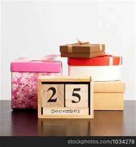 wooden calendar of cubes with the date of December 25 and a stack of boxes with gifts, festive Christmas background