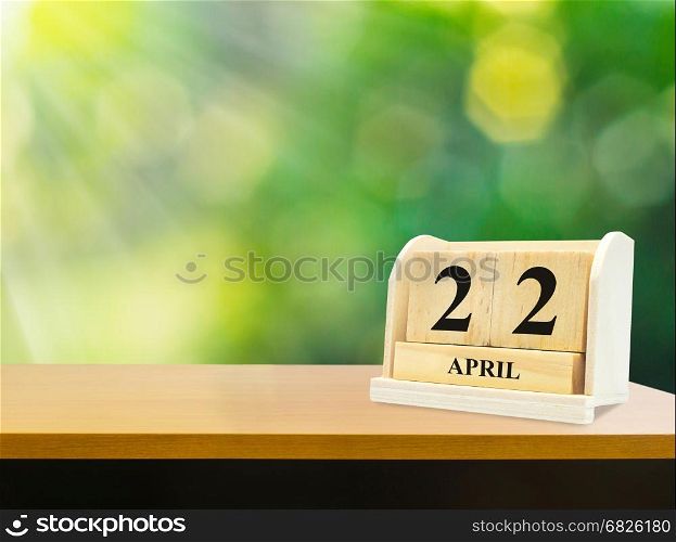 Wooden calendar on wooden desk show the date of April 22 , earth day green bokeh background