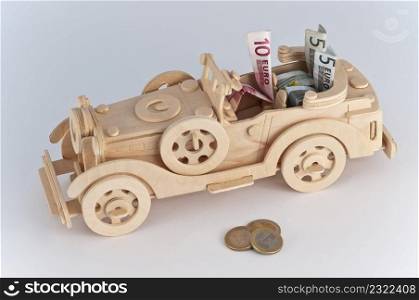 wooden car with bills inside on white background