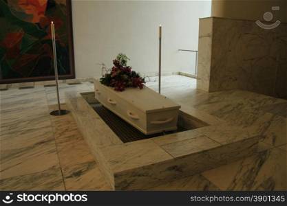 Wooden casket with funeral flowers in a crematorium hall