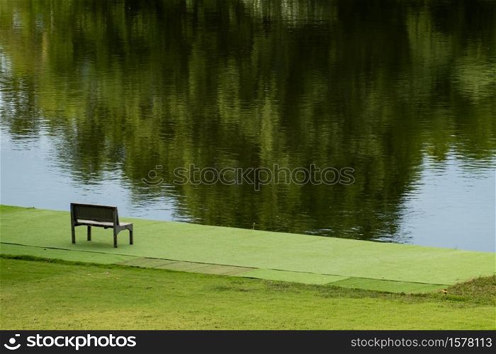 Wooden chair near river and green view.