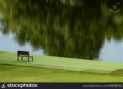 Wooden chair near river and green view.
