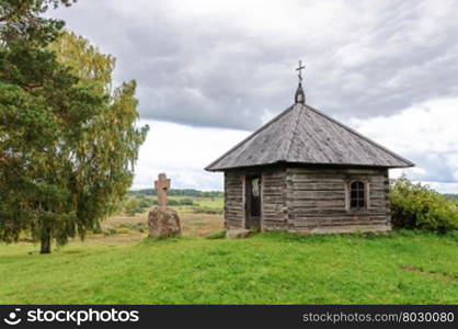 Wooden chapel and stone cross on the top of Savkin hill, Pushkinskiye Gory Reserve, Russia