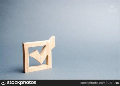wooden checkmark for voting on elections on a gray background. Presidency or parliamentary elections, a referendum. Survey of the population, statistics, task. Democracy and freedom. Selective focus