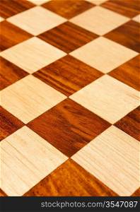 Wooden chess board with brown and yellow squares background . Natural wood