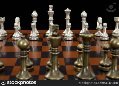 Wooden chess board with metal peices. Shot in studio on black. Nice detail on light pieces.