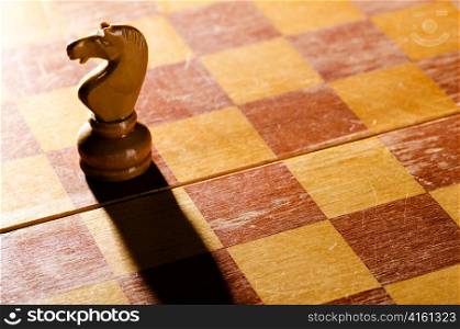 wooden chess knight is standing on board with long shadow