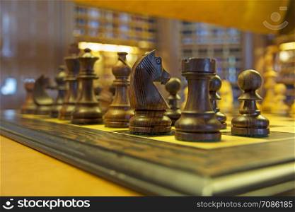 Wooden chess pieces on a chessboard in a ship&rsquo;s library