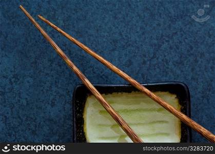 Wooden chopsticks with dish on blue background.