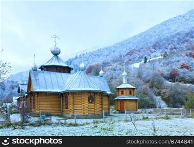 Wooden church and autumn mountain forest with first frost on trees (Carpathian, Ukraine).