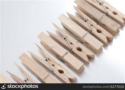 Wooden clothes pegs on silver reflective background.