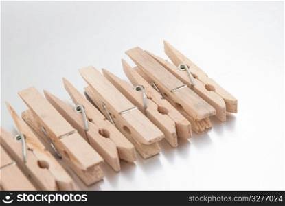 Wooden clothes pegs on silver reflective background.