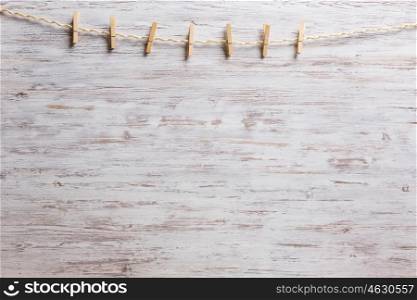 Wooden clothespins on a rope. Old clothespins hanging on rope on wooden background