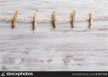 Wooden clothespins on a rope. Old clothespins hanging on rope on wooden background
