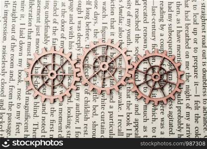 Wooden cogwheels on a page of a book. Industry concept information.