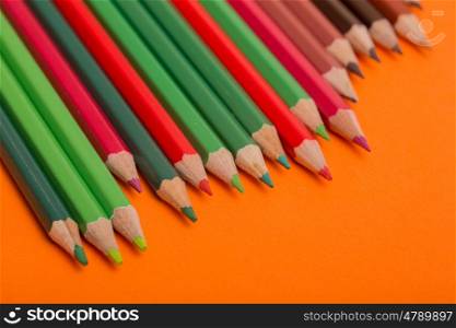 Wooden colorful pencils, on a orange background