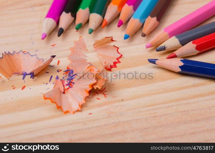 Wooden colorful pencils with sharpening shavings, on wooden table