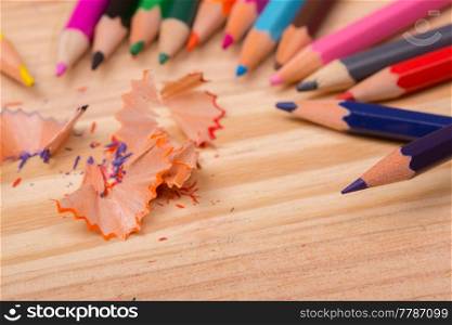 Wooden colorful pencils with sharpening shavings, on wooden table