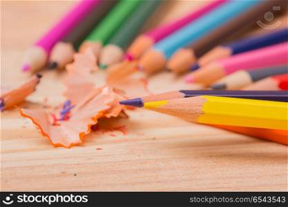 Wooden colorful pencils with sharpening shavings, on wooden table. colorful pencils