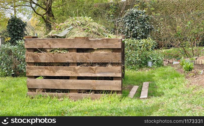 wooden composter full of waste in a garden