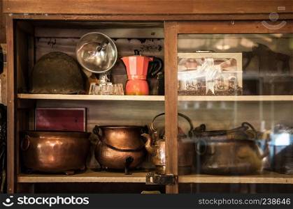 Wooden, copper, metal old vintage pots, jars and coffee pot in a cupboard