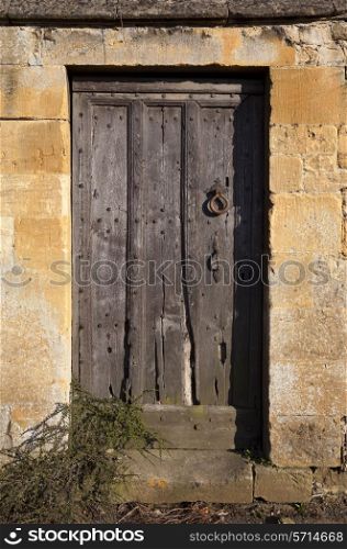 Wooden Cotswold door set into stone wall, Gloucestershire, England.