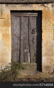Wooden Cotswold door set into stone wall, Gloucestershire, England.