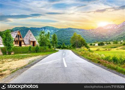 Wooden cotteges near road in mountains of Montenegro at sunset. Cotteges in mountains
