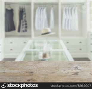 wooden counter top with blur of closet room with white hat and jewelry set on a table