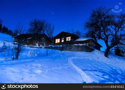 Wooden country house in snow at winter night under blue dark sky with stars