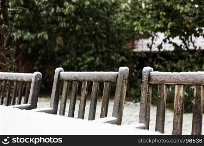 Wooden cozy garden chairs covered in snow in a backyard garden. winter season. Wooden cozy garden chairs covered in snow in a backyard garden.