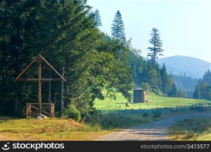 Wooden Cross , haystack and cow on misty morning mountain valley (Carpathian, Ukraine)