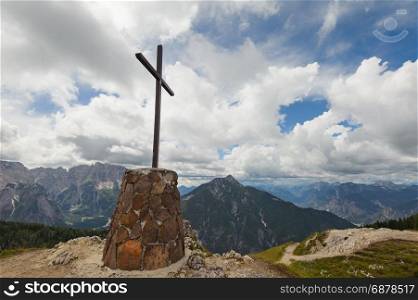 Wooden cross on top of the mountain. Mountain landscape above the clouds. Cross on top of a mountain peak as typical in the Alps.