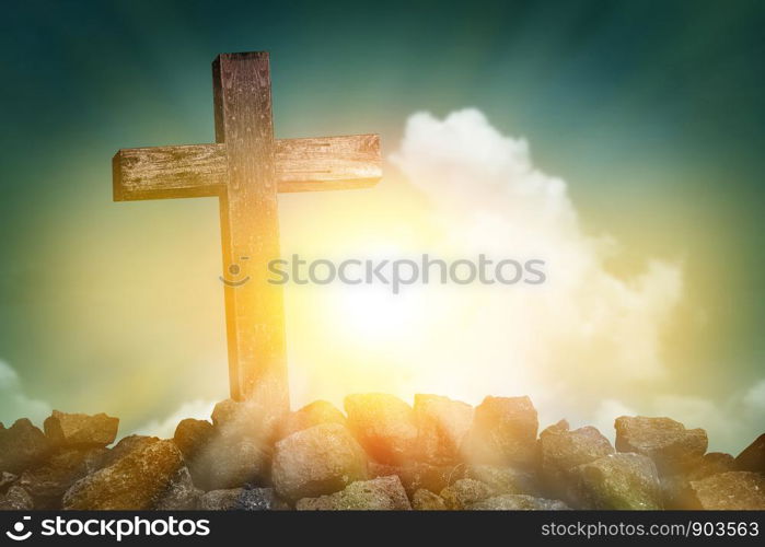 wooden cross shape on rocky hill at sunset with blue sky and clouds background, religion symbol concept